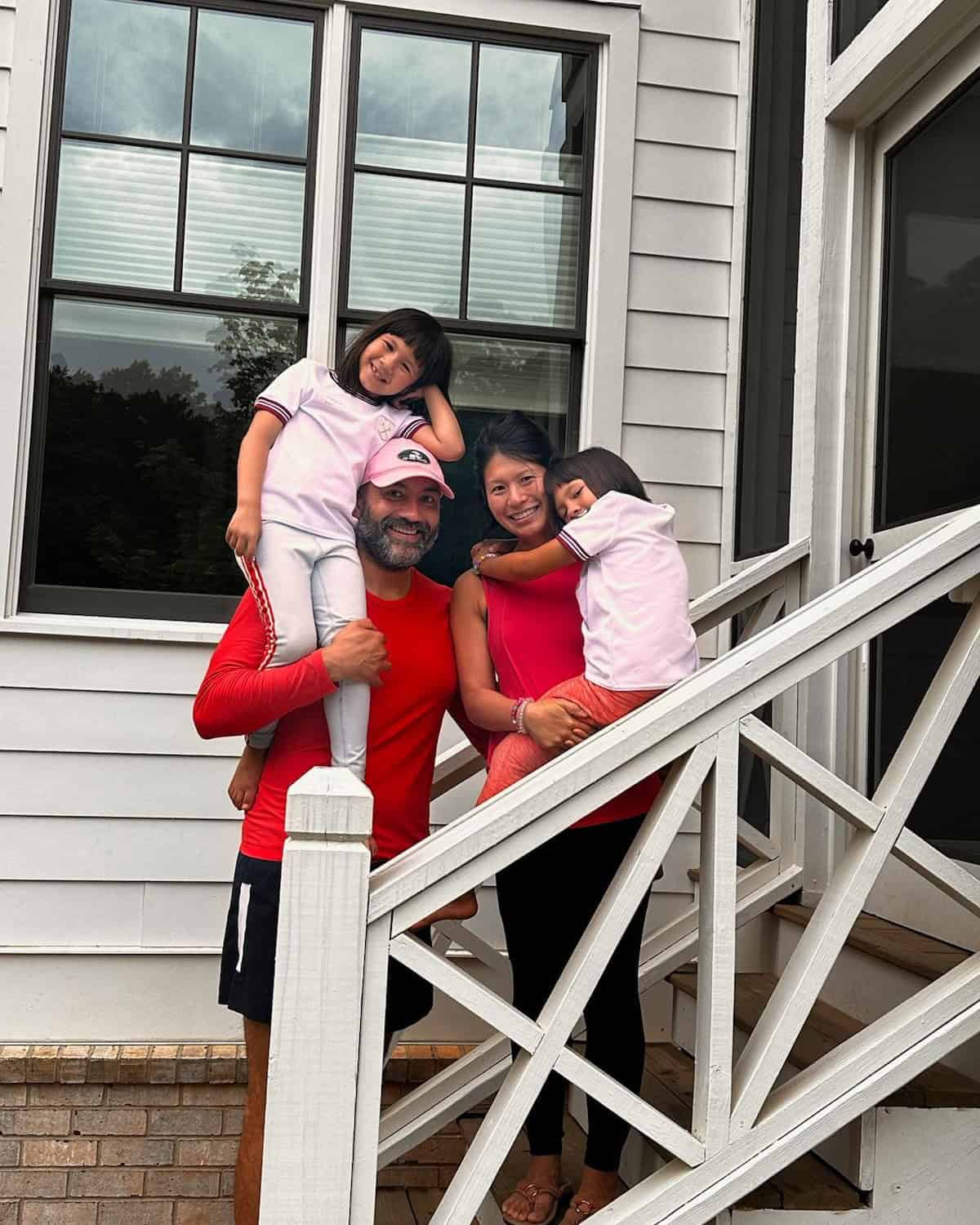 Dow Veeranarong and Marc Aqui with daughters standing on their new home's stairs to front door at Pendergrast Farms